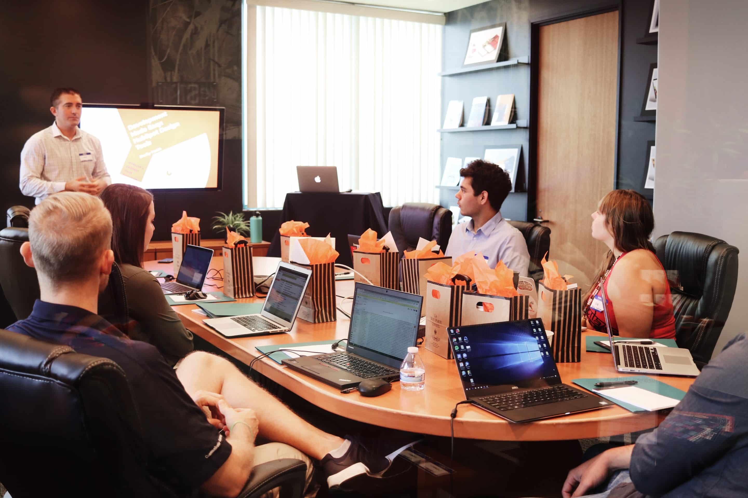 People in a conference room with their laptops listening to a man give a presentation.