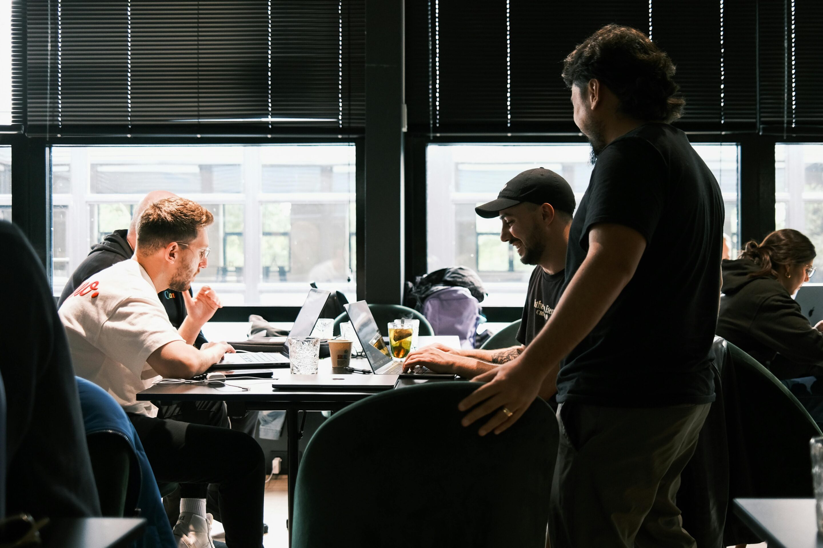 A group of people in a conference room checking their laptops and having a discussion.